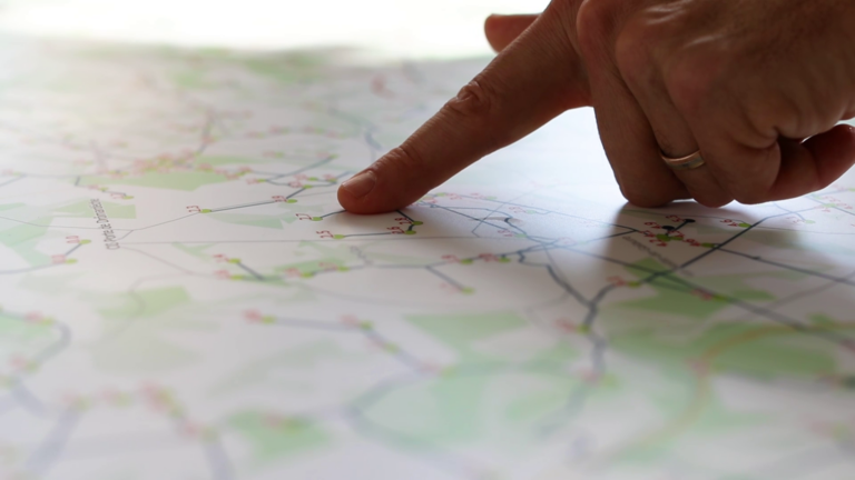 Un doigt tendu qui suit le tracé d'une ligne sur une carte d'un réseau de distribution électrique